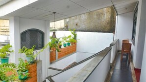 Een balkon met meerdere niveaus, met bloembakken, een houten bankje en uitzicht op de straat.