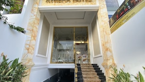 The entrance of Athena Hotel with a marble facade, a staircase leading to the entrance, and a sign above the door.