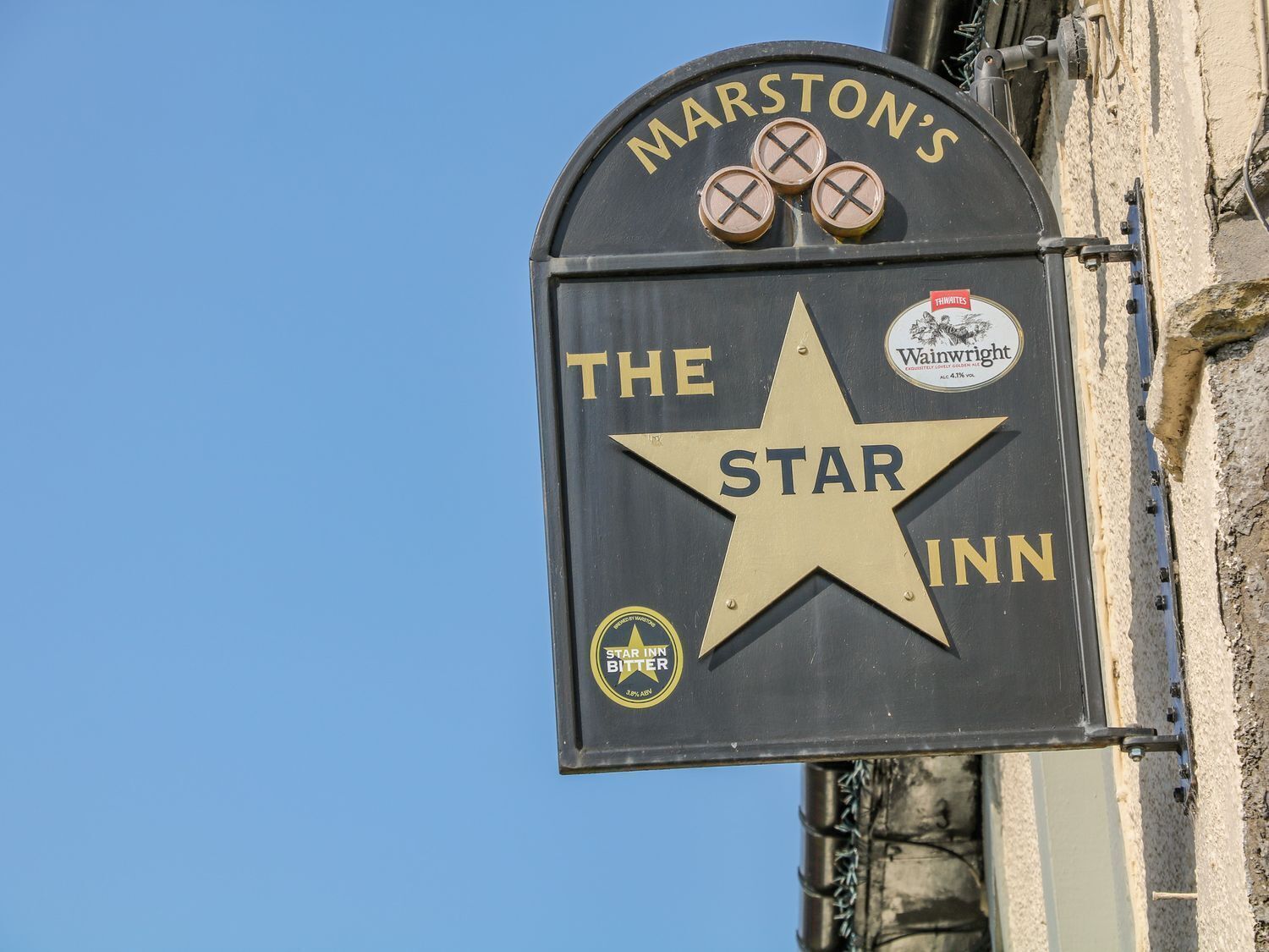 A sign for Marston's The Star Inn, featuring a star emblem and logos for Wainwright and Star Inn Bitter.