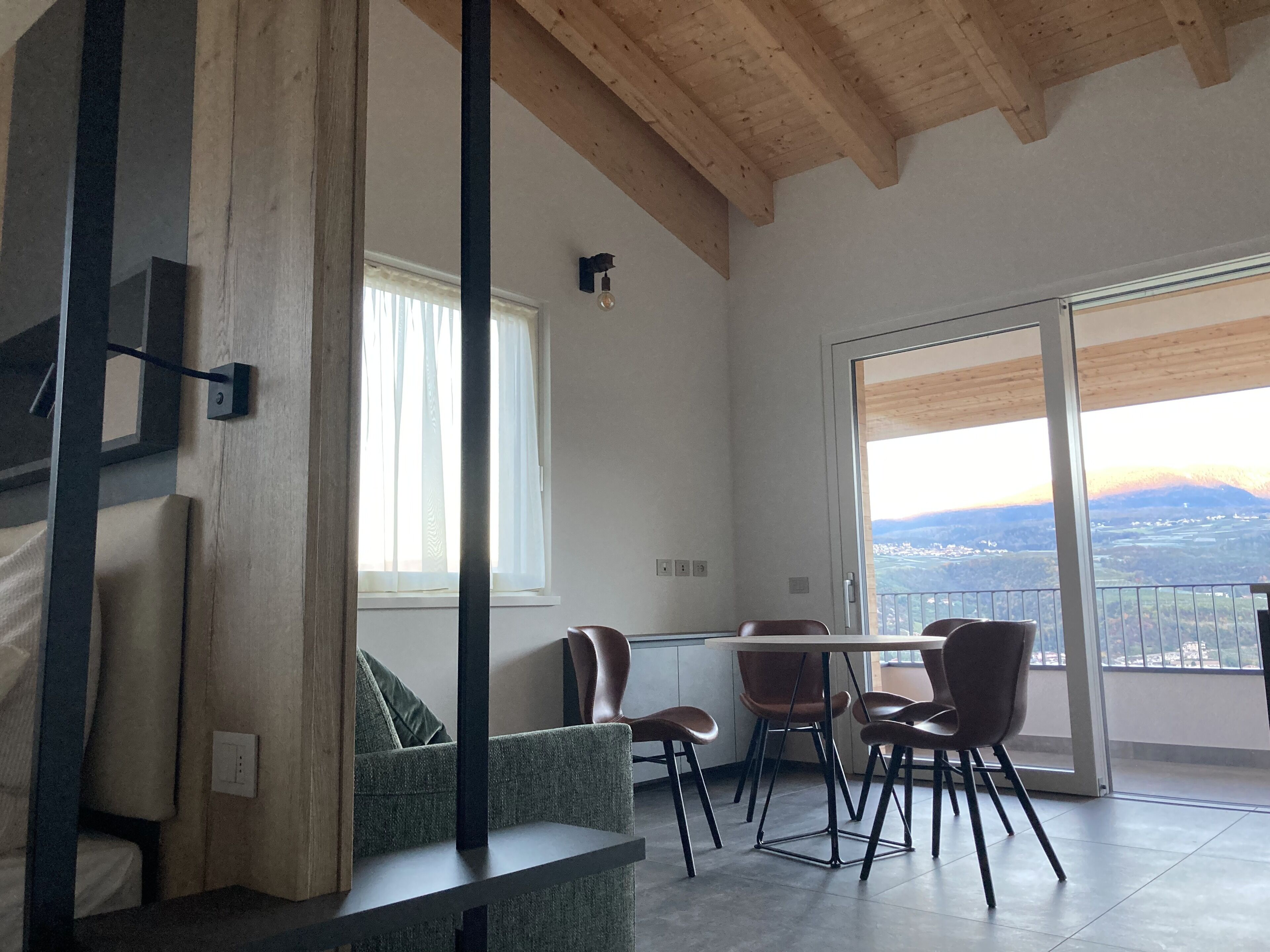 A modern living room with a dining area, large windows, and a view of the countryside.
