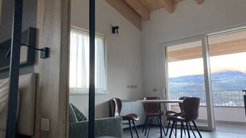 A modern living room with a dining area, large windows, and a view of the countryside.