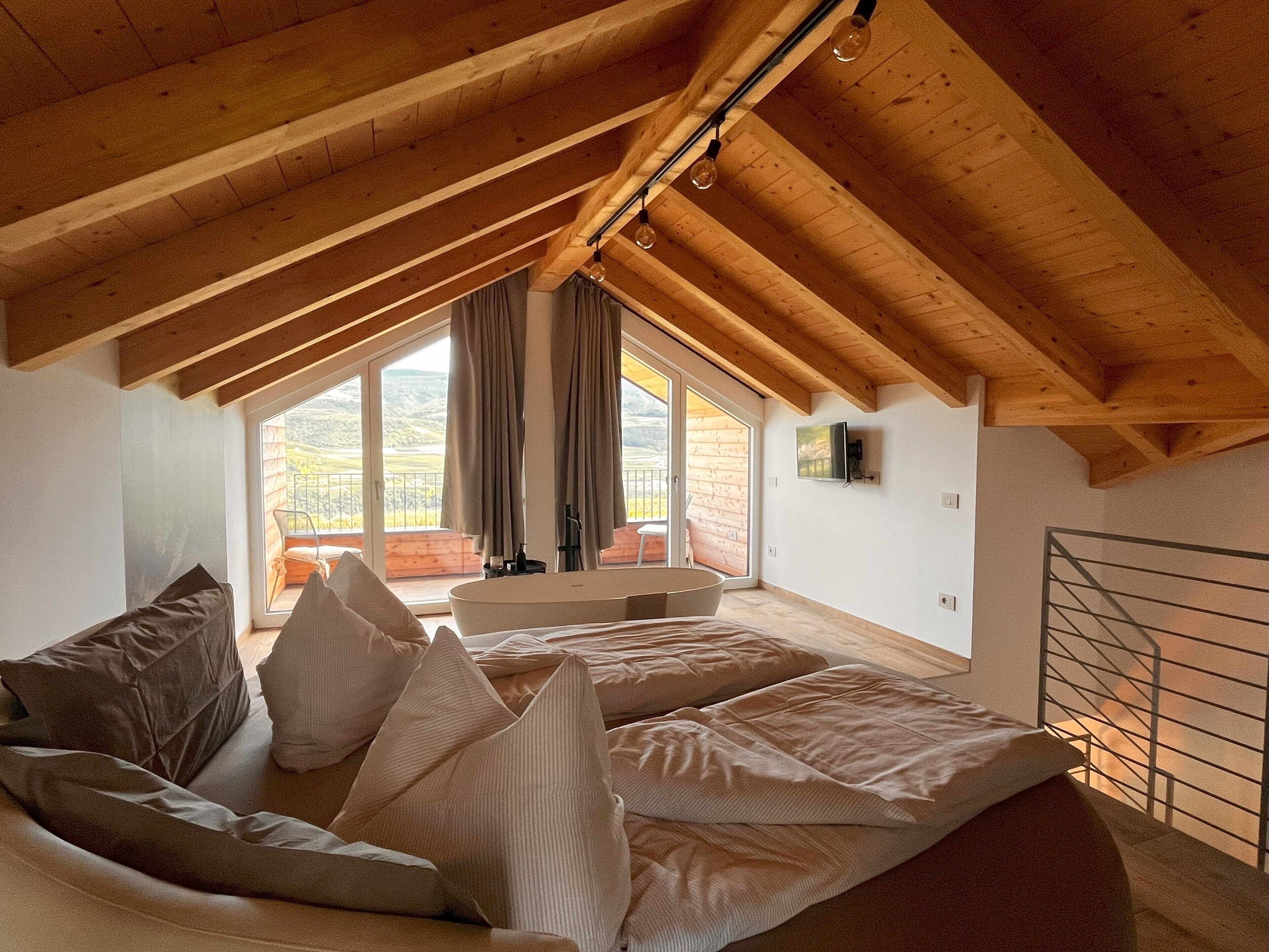 Un dormitorio con techo inclinado, un ventanal y vistas al exterior.