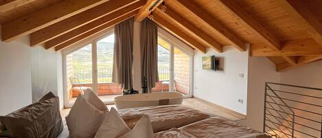Un dormitorio con techo inclinado, un ventanal y vistas al exterior.