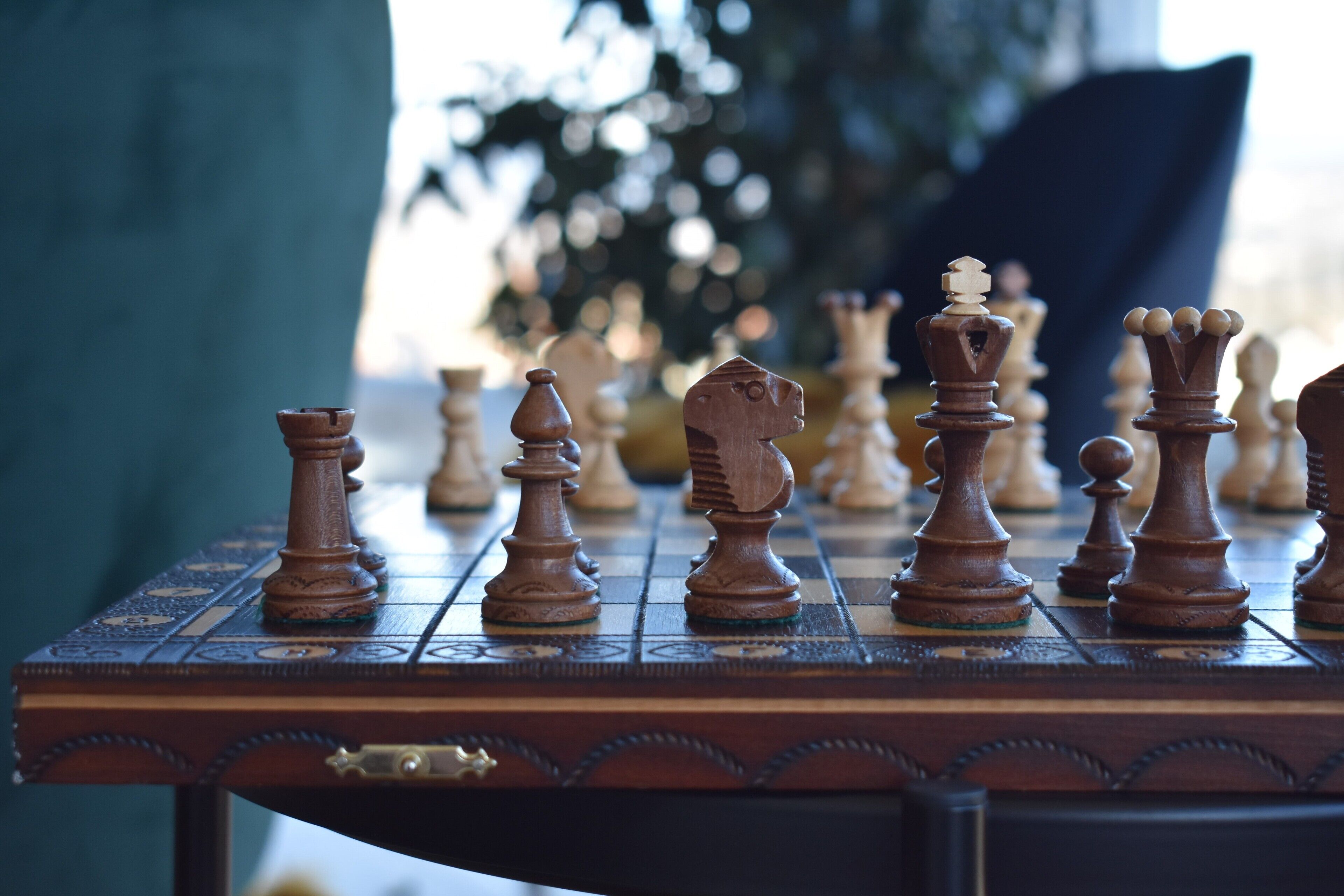 A chessboard with wooden pieces on a table.