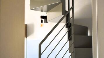 A modern staircase with a metal railing leading to a landing.