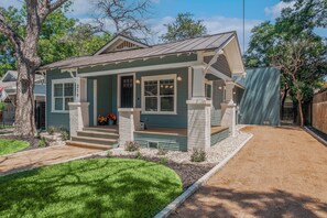 A single-story house with a front porch, a covered entryway, and a small front yard with a lawn and gravel path. - Contemporary Remodeled Bungalow - Pet Friendly! (San Antonio)