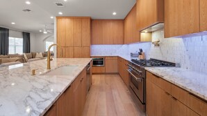 Una cocina moderna con gabinetes de madera, encimera de mármol y electrodomésticos de acero inoxidable.