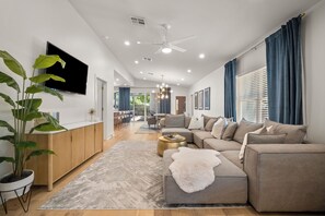 Ein modernes Wohnzimmer mit einer Sofagarnitur, einem Couchtisch und einem an der Wand befestigten Fernseher.