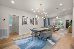 A modern interior with a dining area, sofas, and a kitchen in the background. - Contemporary Remodeled Bungalow - Pet Friendly! (San Antonio)