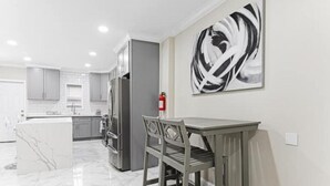 A modern kitchen with grey cabinets, a marble island, and a dining area with a table and chairs. - Fun, Stylish, Pool table, Darts (Camden)