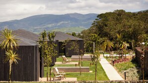 A modern building with a flat roof, surrounded by a well-maintained lawn and a pathway leading to outdoor seating. - Batalha Golf Villas & Spa (Ponta Delgada)