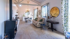 A spacious living room with a sofa, a dining table, and a fireplace. - Batalha Golf Villas & Spa (Ponta Delgada)