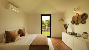 A bedroom with a bed, a bedside table, a window, and a view of the outdoors. - Batalha Golf Villas & Spa (Ponta Delgada)
