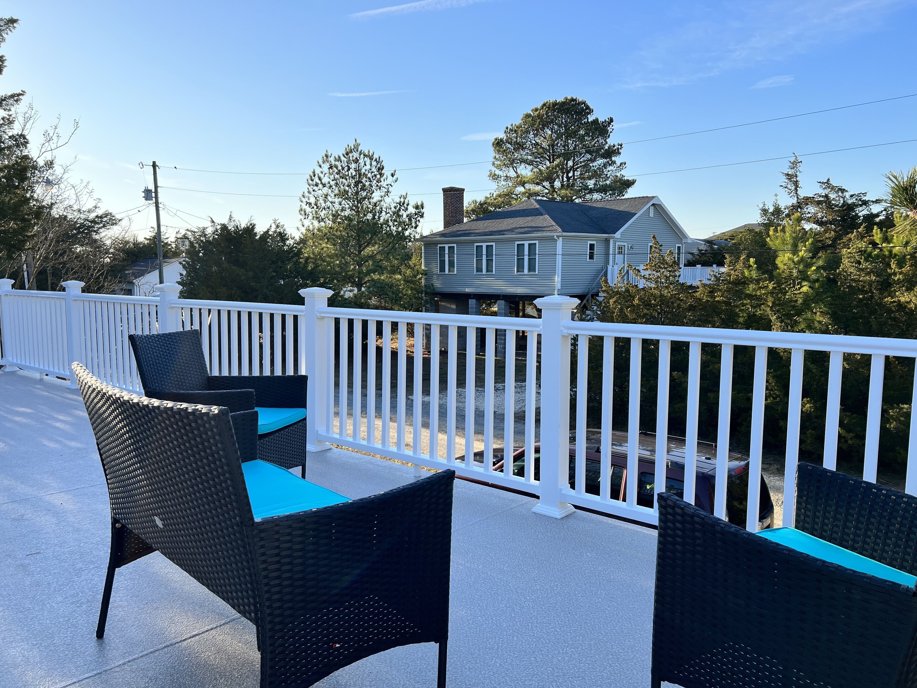 Un balcon avec des fauteuils en osier et une balustrade blanche.