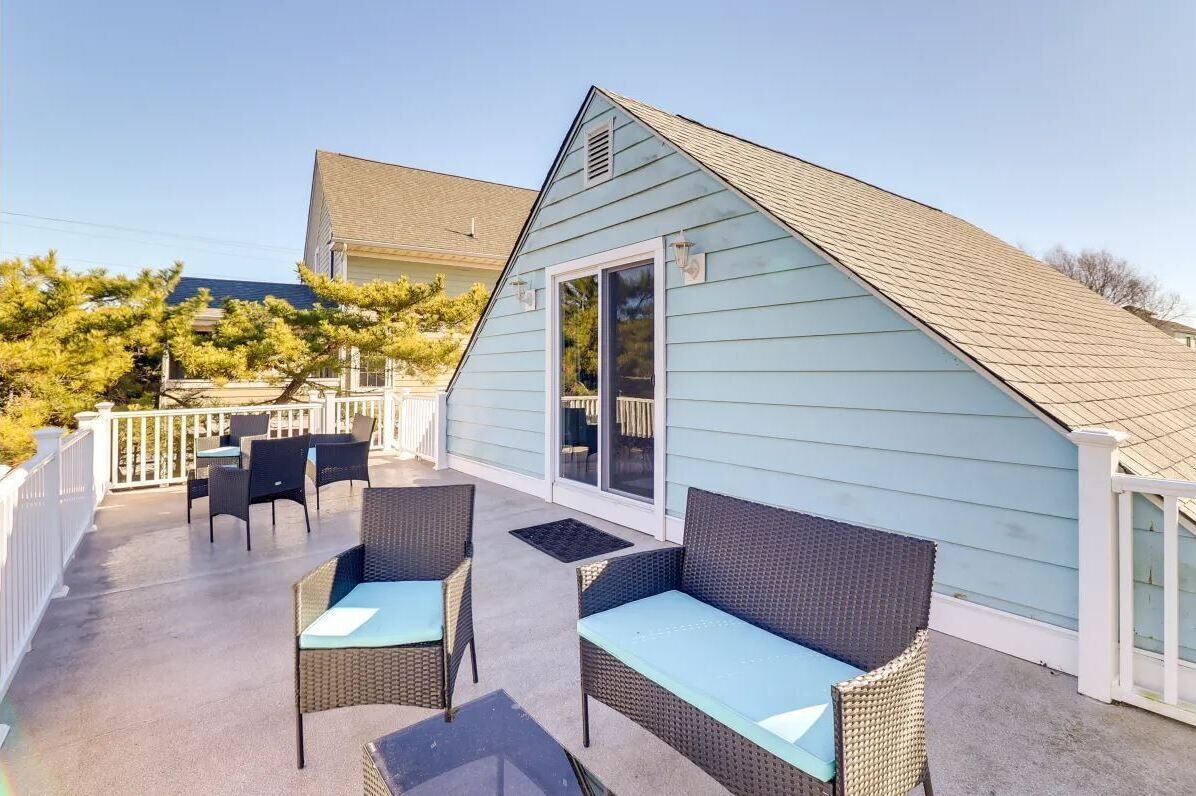Une terrasse couverte, aménagée avec des meubles en osier et dotée d’une porte-fenêtre coulissante.