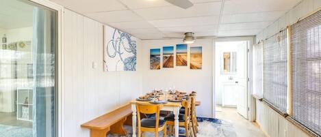 Comedor con mesa dispuesta para seis personas, ventilador de techo y vista hacia otra habitación.