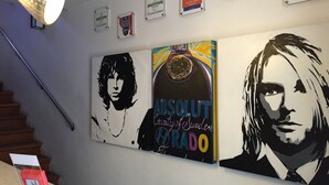 Paredes com quadros de prêmios, uma escadaria e obras de arte retratando um homem e uma mulher.