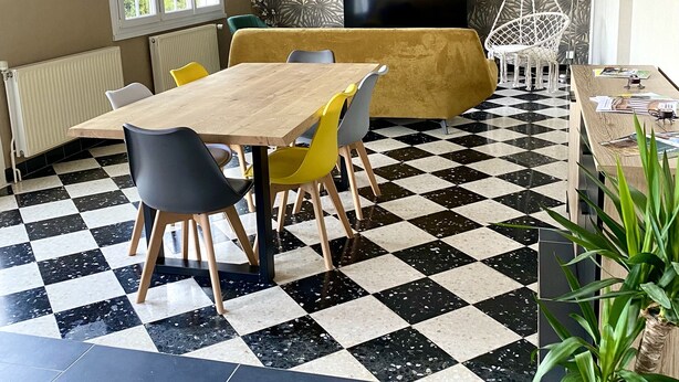 A dining area with a checkered floor, a wooden table, and chairs.