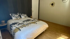 A bedroom with a bed, a nightstand, a wall-mounted light fixture, and a door.