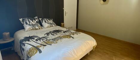 Ein Schlafzimmer mit Bett, Nachttisch, Wandlampe und einer Tür.