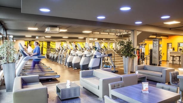 Un gimnasio moderno con cintas de correr, zonas de estar y una escalera.