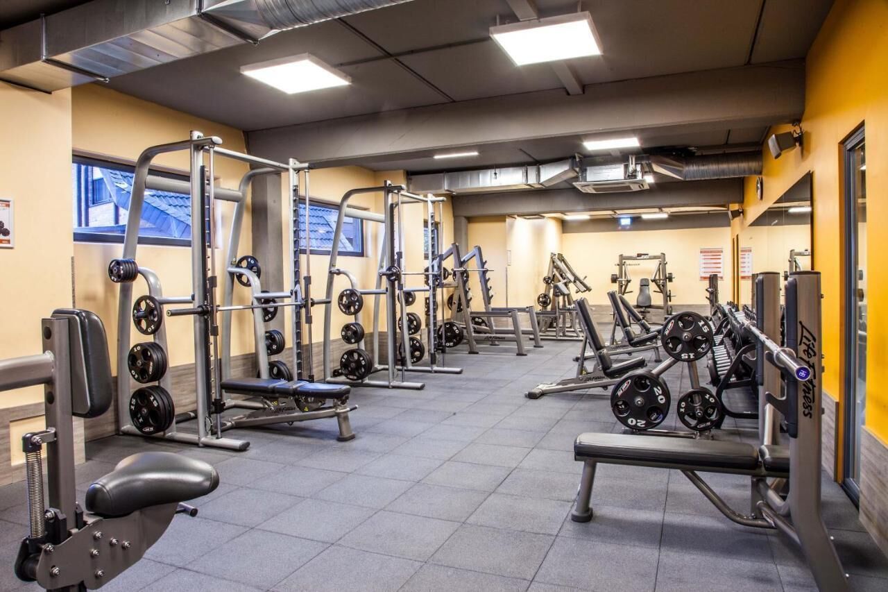A gym with various weightlifting equipment, benches, and weight plates.