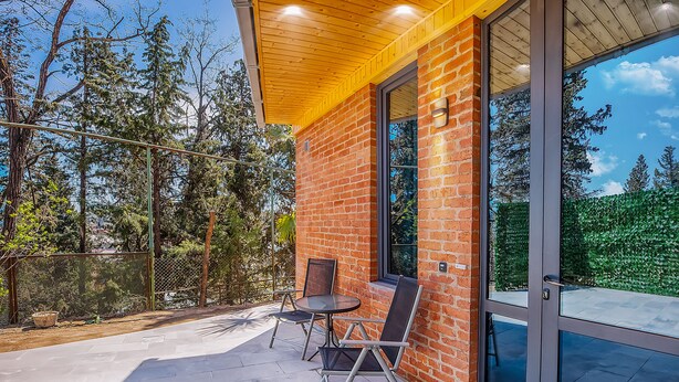 A patio with a brick wall, a glass door, and a table with chairs. - H&B apartments Botsvadze (Tbilisi)