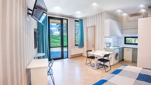 A modern kitchen with a dining area, a flat-screen TV mounted on the wall, and a large window with curtains. - H&B apartments Botsvadze (Tbilisi)