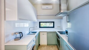 A compact kitchen with a dishwasher, a coffee maker, and a window above the sink. - H&B apartments Botsvadze (Tbilisi)