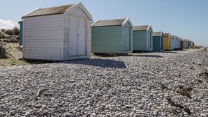 A row of beach huts with a gravel beach in the foreground. - Easter Blervie (Forres)