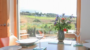 A dining table with a vase of flowers, two wine glasses, and plates set for a meal. - Easter Blervie (Forres)