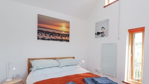 A bedroom with a bed, a nightstand, a desk, a window, and artwork on the walls. - Easter Blervie (Forres)