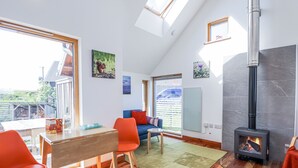 A modern living room with a high ceiling, skylight, and a wood-burning stove. - Easter Blervie (Forres)