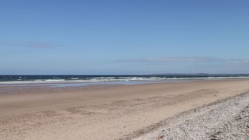 Uma praia extensa com céu claro.
