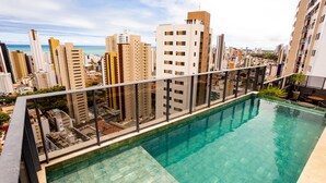Una piscina al terrat amb vista a la ciutat, envoltada d'edificis alts.