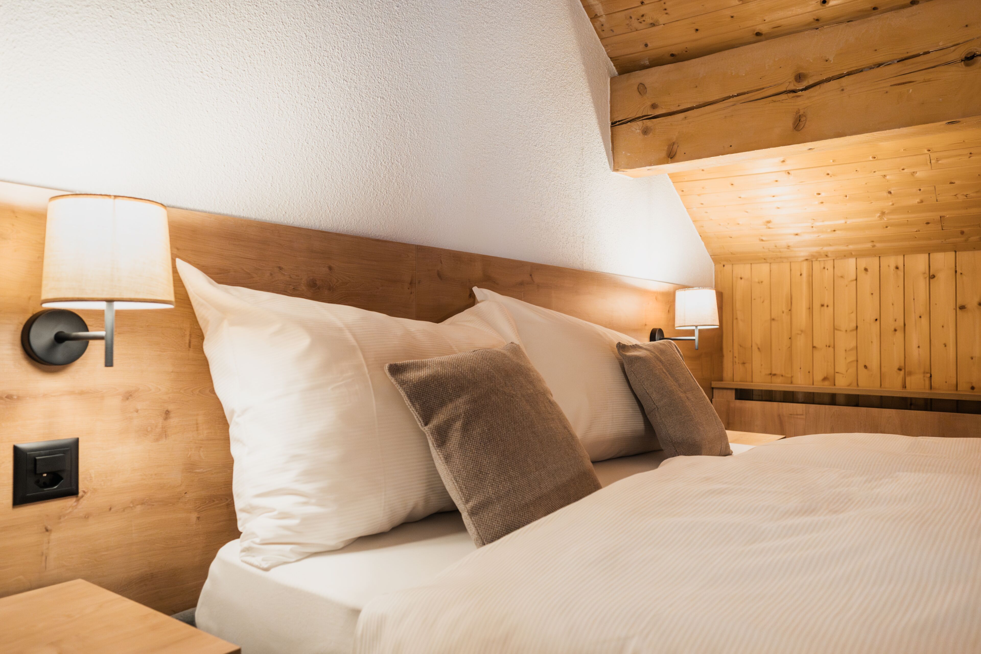 Ein Zimmer mit Holzwandverkleidung, einem Bett, zwei Wandlampen und einem Nachttisch.