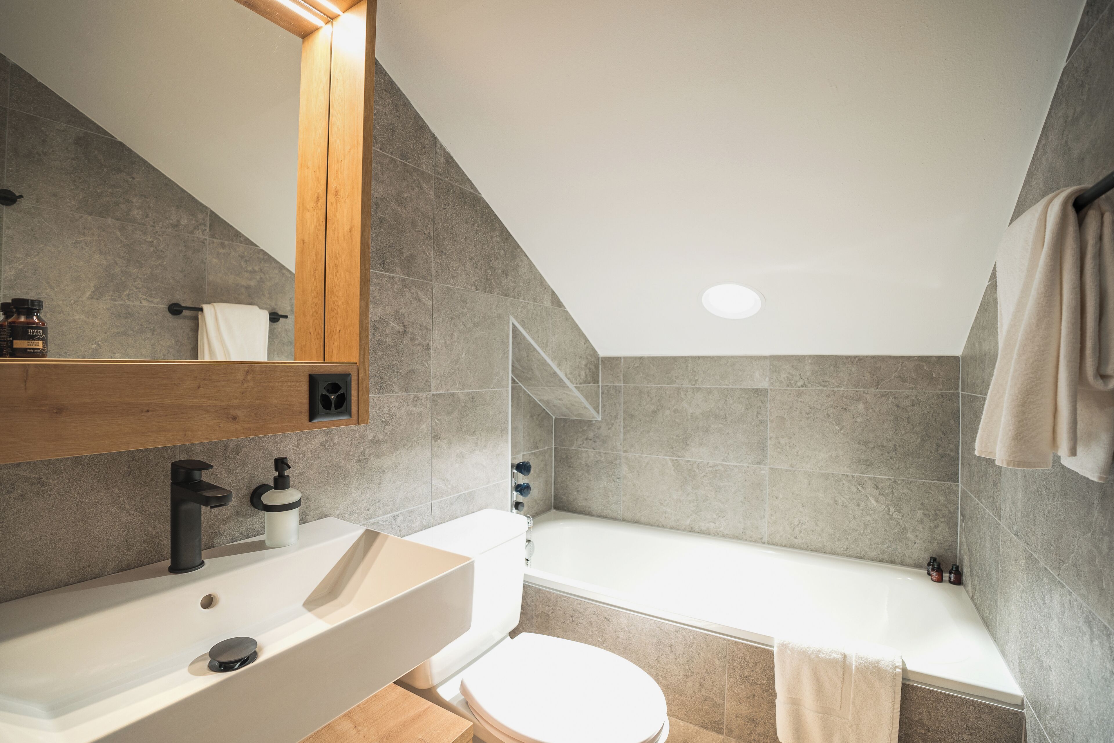 Ein modernes Badezimmer mit einem weißen Waschbecken, einem schwarzen Wasserhahn und einer weißen Toilette.