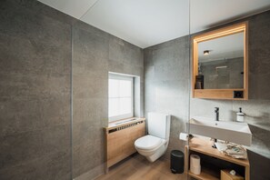 Uma casa de banho moderna com sanita, lavatório e janela.