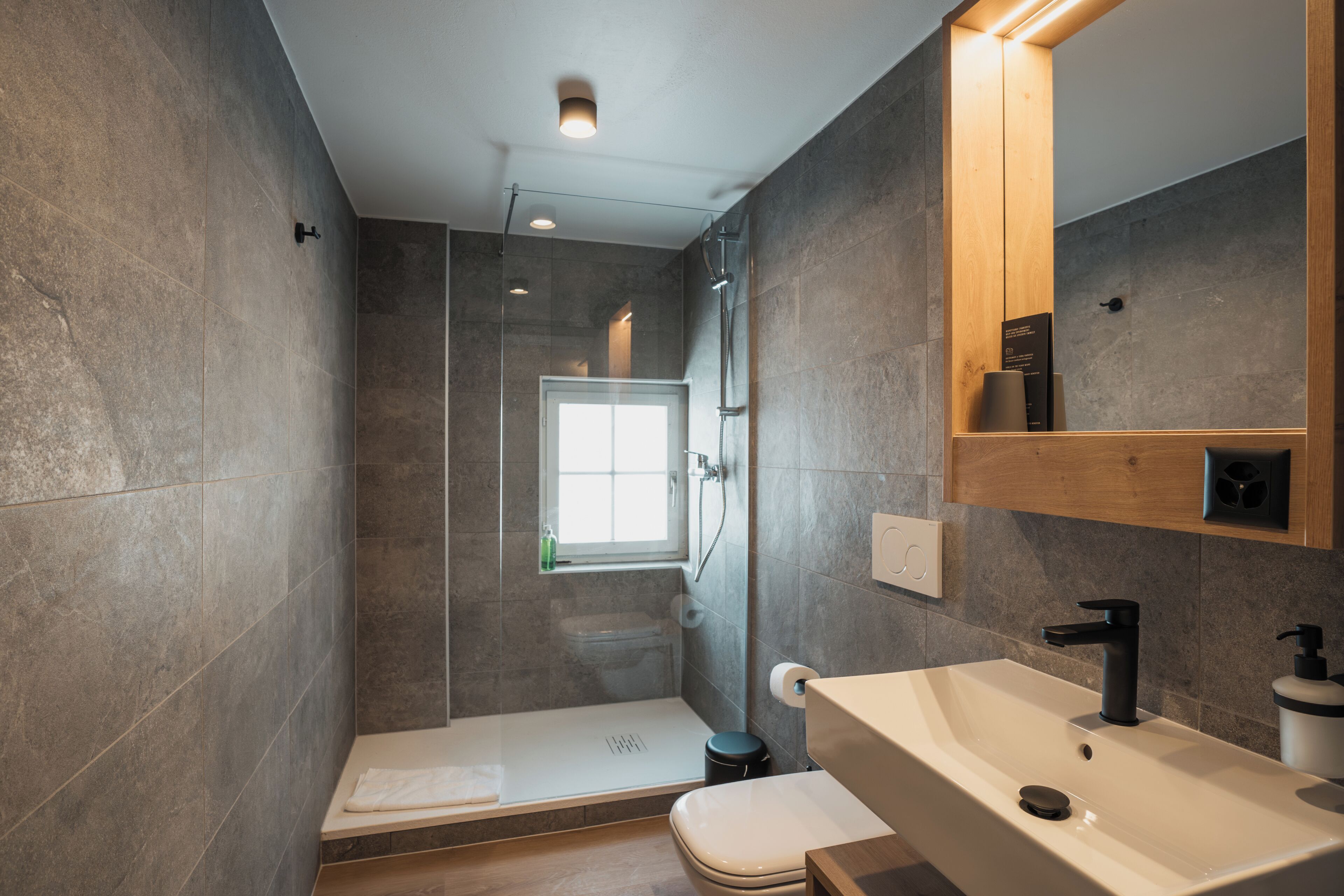 A modern bathroom with a shower, toilet, and sink.