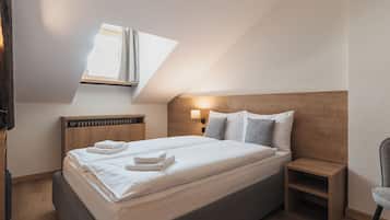Ein Schlafzimmer mit Bett, Nachttisch, Lampe und Fenster.