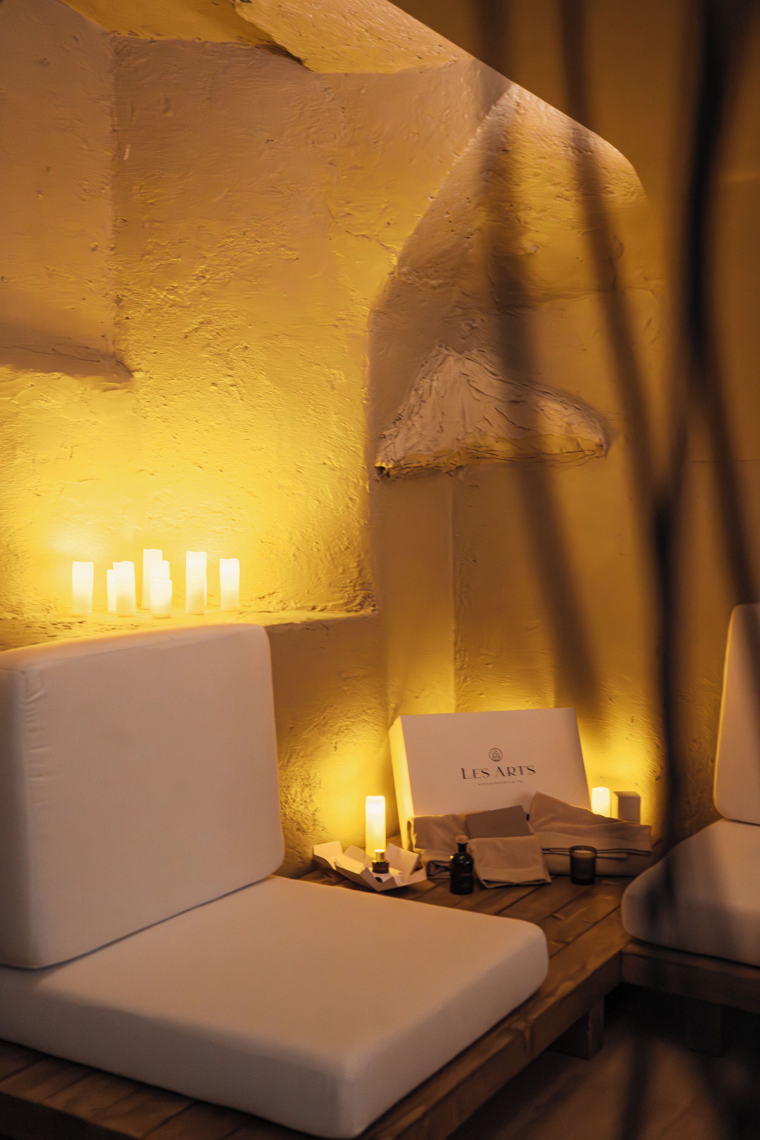 Una habitación acogedora con un sofá blanco, una mesita con velas y una lámpara.