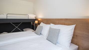Une chambre d’hôtel avec un lit superposé, une tête de lit en bois et une table de chevet avec une lampe.