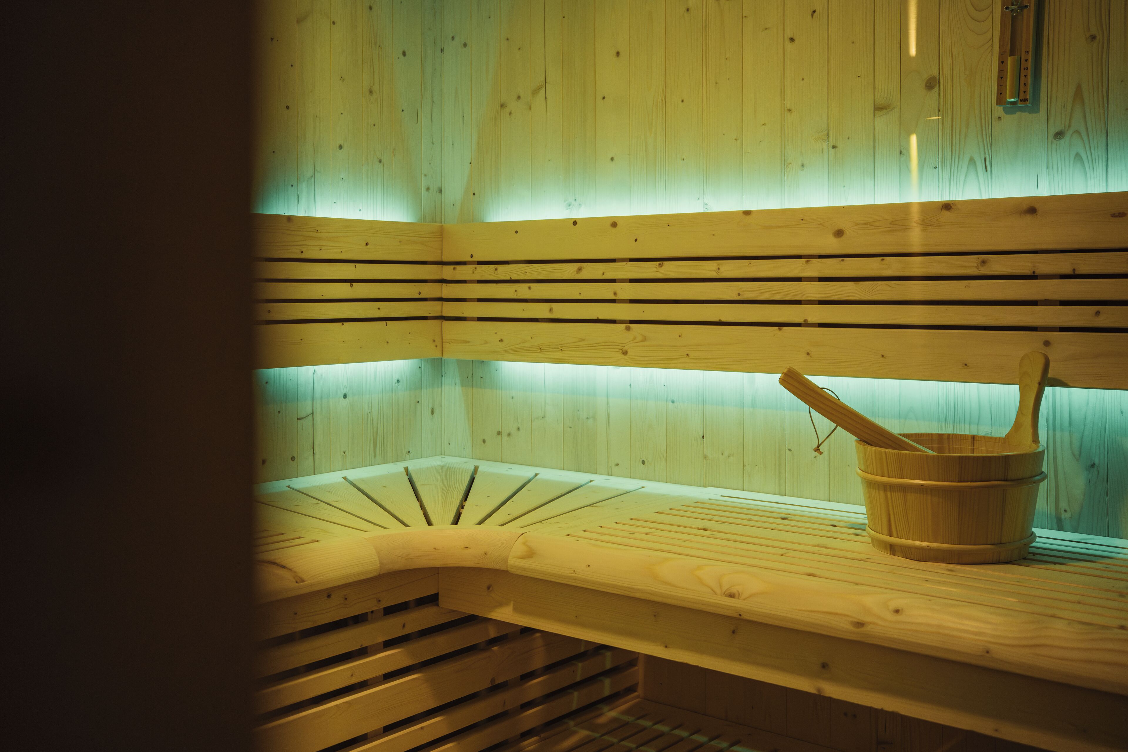 Una sauna amb seients de fusta i un cub de fusta.