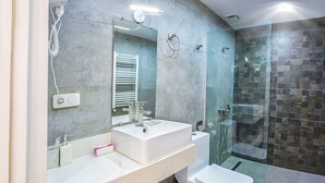 Een moderne badkamer met een grote spiegel, een witte wastafel en toilet.