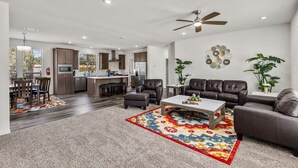 A spacious living area with a large sofa, a coffee table, and a dining area with a rug. - Andante Trail - Unit A - Red Rock Retreat (Sedona)