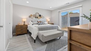 A bedroom with a bed, bedside tables, a bench, a dresser, and a wall with decorative plates. - Wine Lovers Paradise (Lodi)