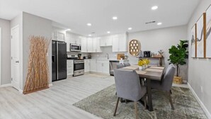 A modern kitchen with white cabinets, a black refrigerator, and a microwave. - Wine Lovers Paradise (Lodi)