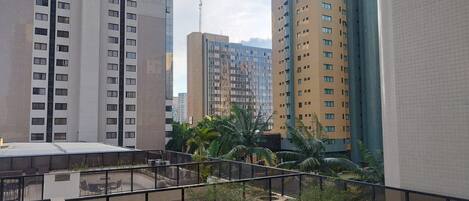 Un edificio alto con varios pisos, un jardín en la azotea con asientos y vistas a otros edificios.