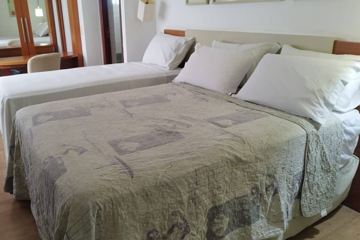 A hotel room with two beds, a wooden desk, and a chair.