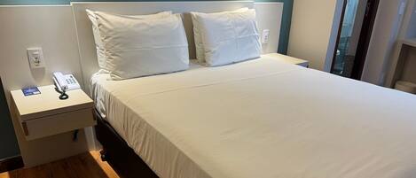 Una cama bien hecha con sábanas blancas en una habitación de hotel.